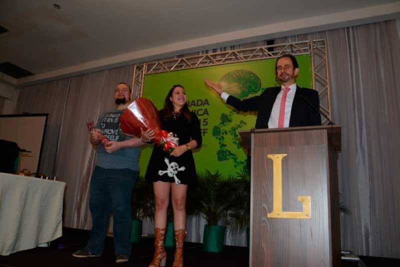Daniel Bizon e dois estudantes sendo homenageados no palco Daniel Bizon e dois estudantes sendo homenageados no palco