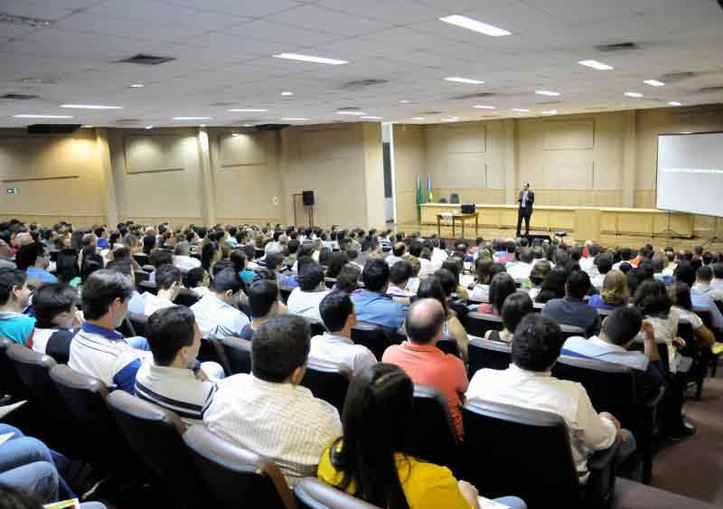 Grande platéia atenta ao palestrante no palco Grande platéia atenta ao palestrante no palco
